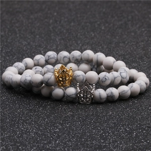 Vista dettagliata di bracciali con perline di marmo bianco e ciondoli corona oro e argento