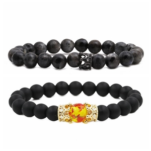 Vista de detalle de dijes de corona en pulseras de cuentas de piedra natural negra y gris
