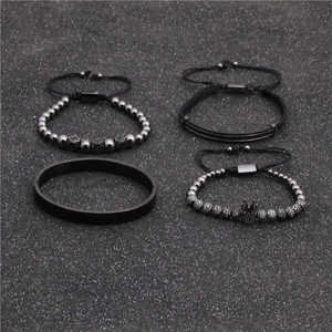 Dettaglio di un set di 4 bracciali da uomo con ciondolo a corona e polsino nero opaco