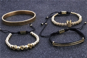 Dettaglio di quattro bracciali con corona dorata e numeri romani su superficie nera