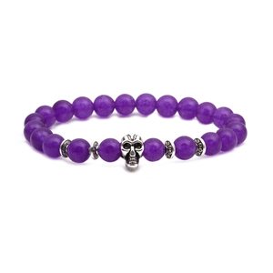Détail d'un bracelet de perles violettes avec un charme en forme de crâne argenté