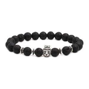 Vue macro de perles en pierre de lave et charme tête de lion sur un bracelet élastique