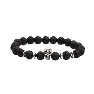 Vue macro des perles de lave noire avec un charm crâne en argent détaillé sur un bracelet