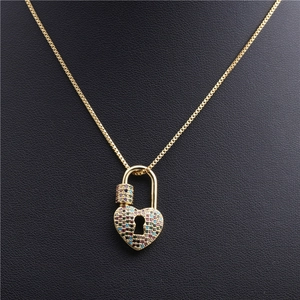 Vue détaillée d'un collier chaîne dorée avec un pendentif cadenas cœur serti de zircons colorés