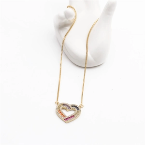 Détail du collier cœur avec pierres baguette arc-en-ciel et zircons sur une chaîne dorée