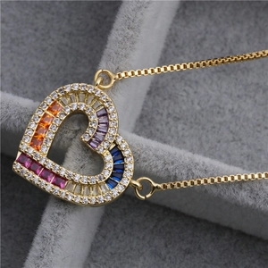Détail d'un pendentif cœur doré avec gemmes colorées et cristaux en micro-pavage