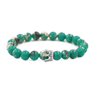Close-up of 8mm green imperial stone beads with a silver crown charm on a bracelet