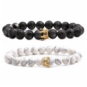 Stack of white marble and grey stone bead bracelets with golden crown charms and crystals