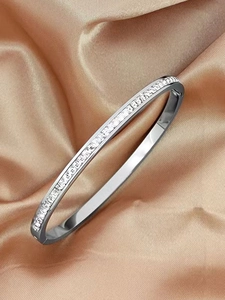 Macro shot of silver stainless steel oval bracelet with crystal inlay on silk fabric