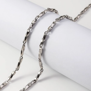 Polished silver Mobius twisted link necklace draped over a white cylinder pedestal