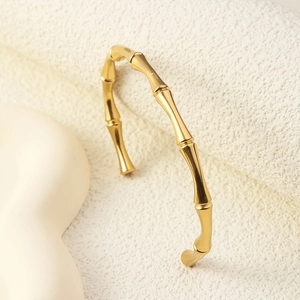 Elegant gold bamboo joint bangle with adjustable open design on a minimalist stone base