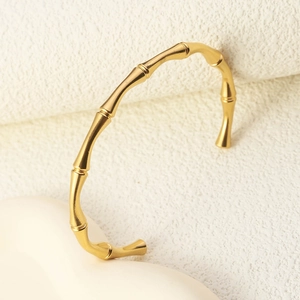 Macro detail of the bamboo joint design and brushed golden texture on an open bangle