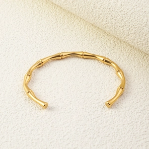 Detailed close-up of golden stainless steel bangle with a unique bamboo-style texture