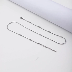 Detail van een zilveren roestvrijstalen slangenketting met kleine kralen en een karabijnsluiting