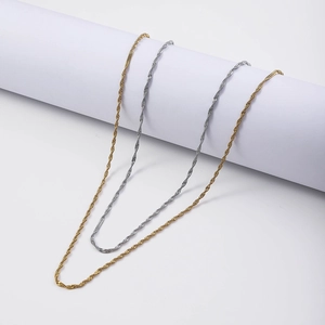 Detailed view of gold and silver twisted rope chains on a minimalist white pedestal