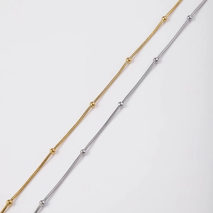 Detail van vergulde en verzilverde roestvrijstalen slangenschakelketting met kralen
