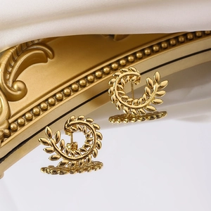 Detail von goldenen Weizenähren-Ohrsteckern mit poliertem Finish auf Spiegelfläche