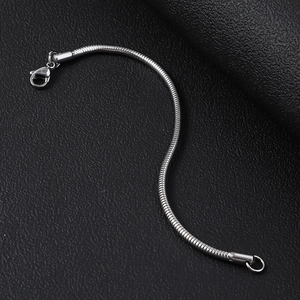 Nahaufnahme eines silbernen Schlangenkette-Armbands mit Karabinerverschluss auf Schwarz