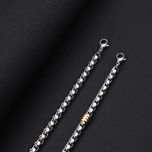 Macro shot of stainless steel box chain necklace with gold rings and lobster clasp