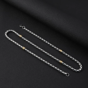 Detail of stainless steel chain necklace with contrasting gold textured beads