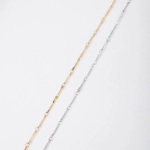 Detailaufnahme dünner zylindrischer Gliederketten in Gold und Silber auf weißem Grund