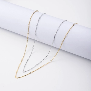 Detail von minimalistischen 18k Gold und Silber Halsketten auf einem weißen Zylinder