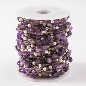Detailed macro view of purple amethyst stone and pearl beads on golden DIY chain roll