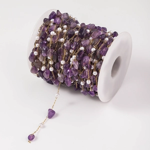 Detail of DIY jewelry chain with purple crystal stone and white pearls on gold wire spool
