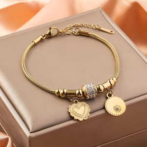 Detail of gold snake chain bracelet with heart charm and sparkling rhinestone beads