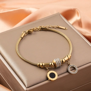 Close-up of golden snake chain bracelet with sparkling charms on luxury satin backdrop