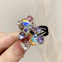 Close-up of elastic hair tie featuring a sparkling teddy bear pendant with colorful rhinestones
