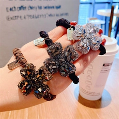 Close-up of high elasticity hair ties featuring crystal floral charms in warm cafe setting
