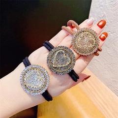 Detail view of elastic hair ties featuring round rhinestone charms with heart patterns