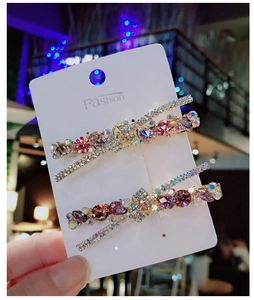 Dettaglio di fermagli per capelli a X con strass scintillanti rosa e viola