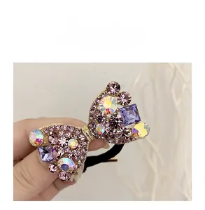 Détail d'un élastique à cheveux nœud doré avec strass multicolores et lien noir souple