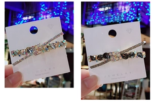 Dettaglio di fermagli per capelli in strass a forma di X in tonalità oro e grigio