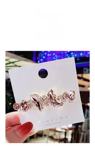 Close-up of pink crystal hair clip with wave design on a white jewelry card