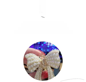 Dettaglio di una pinza per capelli a fiocco con perle bianco crema e molla in metallo