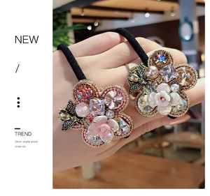 Detail of flower hair tie with multi-color zircon crystals, pearls and a small metal bee