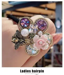 Detail of flower hair tie with purple crystal, pearl, resin rose and metal bee decoration