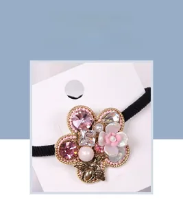 Close-up of Baroque five-petal flower hair tie with pink rhinestones and a metal bee charm