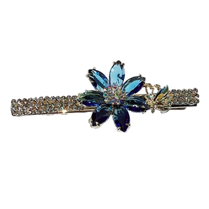 Barrette fleur en cristal avec strass bleus et détail papillon doré élégant