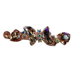 Vintage gold hair clip with amber crystal stones and iridescent rhinestones on white background