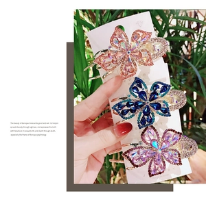Detailed view of floral crystal hair clips with sparkling rhinestones in three colors