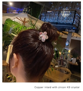 Close-up of pink crystal flower hair tie worn on a bun, featuring baroque pearl accents