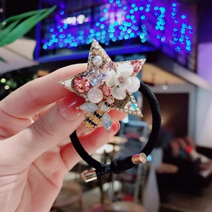 Close-up of star-shaped hair tie with pearls, crystals, ceramic flowers and a bee charm