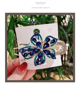 Detail of blue crystal five-petal flower hair claw clip with rhinestones and metallic finish