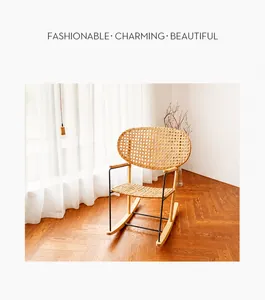 Détail d'une chaise à bascule en rotin tressé avec dossier rond et structure en métal noir