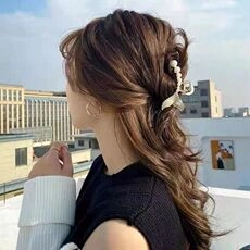 Detail of elegant pearl fishtail hair claw clip styled on a woman's half-up hairstyle