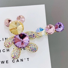 Macro detail of bear hair clip featuring yellow and purple crystals with tiny rhinestones
